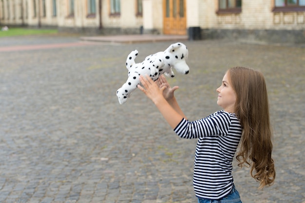 La vie pleine de plaisir. Un enfant heureux joue avec un chien jouet à l'extérieur. Profiter de la récréation. Jouer et s'amuser. Amusement d'enfance. Loisirs et temps libre. Jeux actifs. Vacances d'été. Journée internationale des enfants, espace de copie.