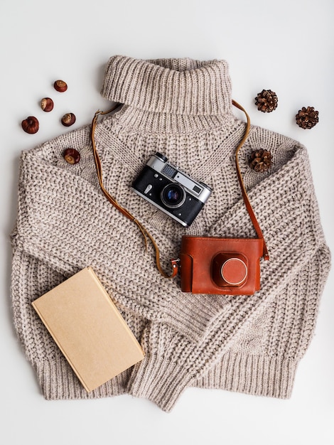 Un vieil appareil photo et un livre sur un pull en laine