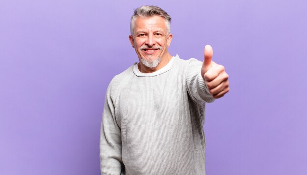 Vieil homme âgé se sentant fier, insouciant, confiant et heureux, souriant positivement avec le pouce levé