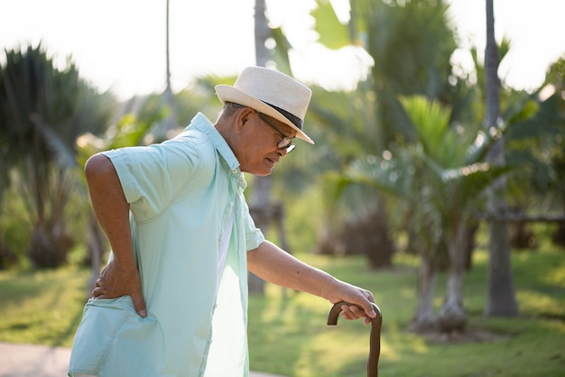 Vieil homme asiatique marchant dans le parc et ayant des maux de dos, maux de dos.