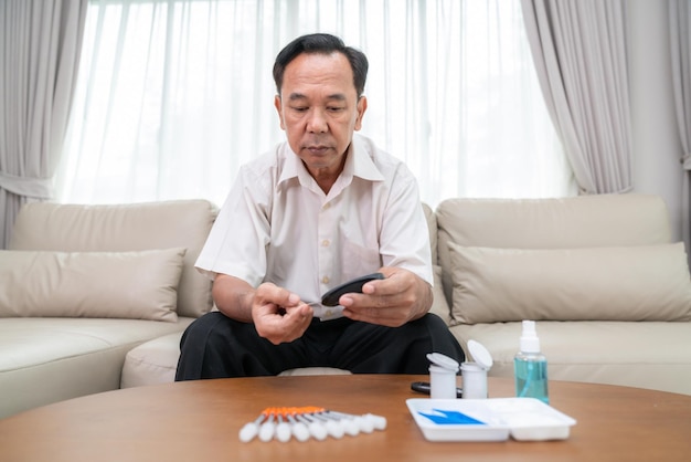 Photo un vieil homme asiatique vérifie lui-même son taux de sucre dans le sang à la maison pour contrôler l'insuline, le diabète et le contrôle de la santé à son doigt.