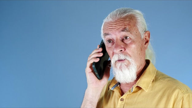 Le vieil homme aux cheveux blancs parle sur le téléphone portable Photo