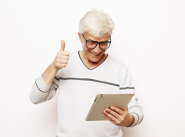 Un vieil homme aux cheveux gris communique avec sa famille sur une tablette