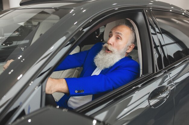 Vieil homme beau à l'intérieur de la voiture. Mâle barbu mature dans l'automobile. Homme d'affaires confiant d'acheter la voiture.