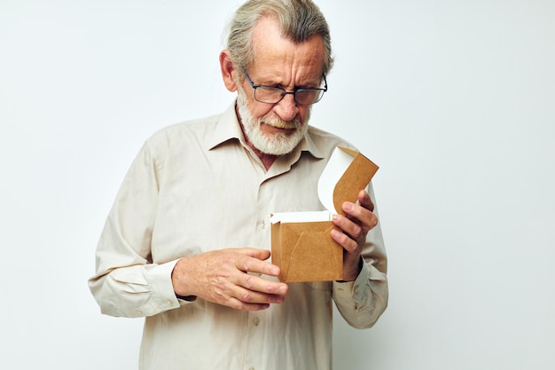 Vieil homme avec une boîte dans ses mains en studio seul