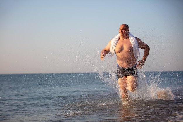 Un vieil homme court le long de la plage