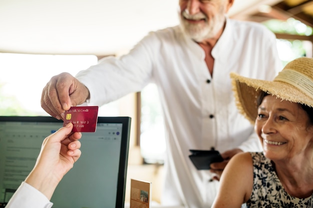 Photo vieil homme donnant une carte de crédit à la réceptionniste