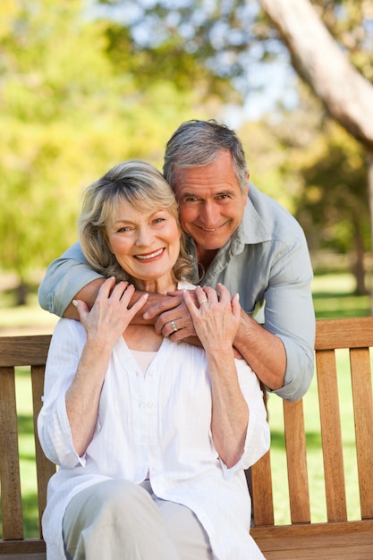 Vieil homme embrassant sa femme qui est sur le banc