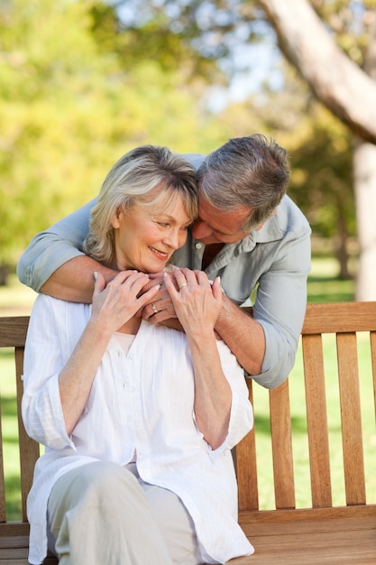 Vieil homme embrassant sa femme qui est sur le banc