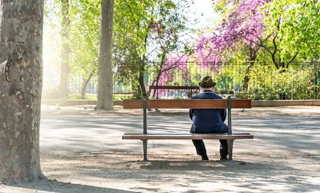 Vieil homme espagnol assis relaxant sur un banc dans le parc du Retiro à Madrid, Espagne - mise au point sélective.