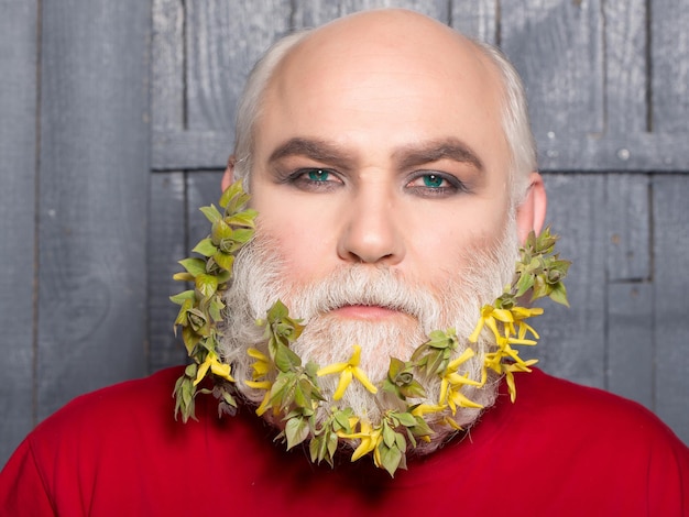 Vieil homme avec des fleurs et des feuilles dans la barbe