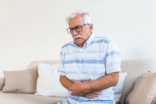 Un vieil homme avec de fortes douleurs abdominales, des problèmes de santé, un homme âgé avec des douleurs à l'estomac.