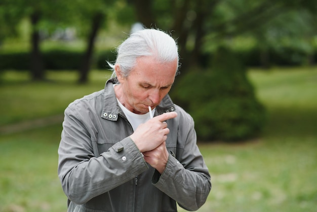 Un vieil homme fumant une cigarette à l'extérieur de la mauvaise habitude de la dépendance à la fumée