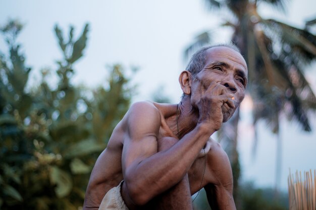 Le vieil homme fume des cigarettes.