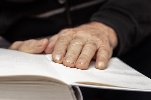 Un vieil homme un grand-père tient un livre ouvert dans ses mains Loisirs pour les personnes âgées Lire un livre