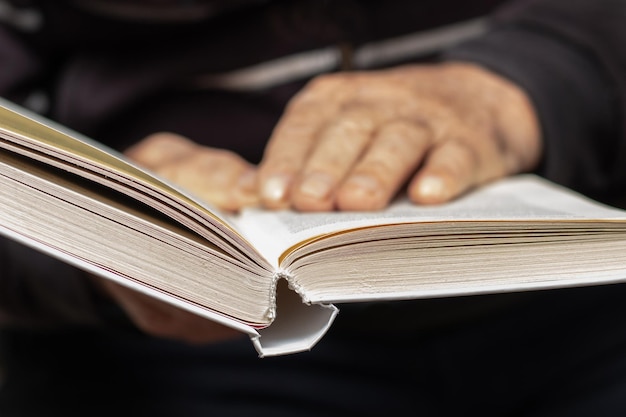 Un vieil homme un grand-père tient un livre ouvert dans ses mains Loisirs pour les personnes âgées Lire un livre