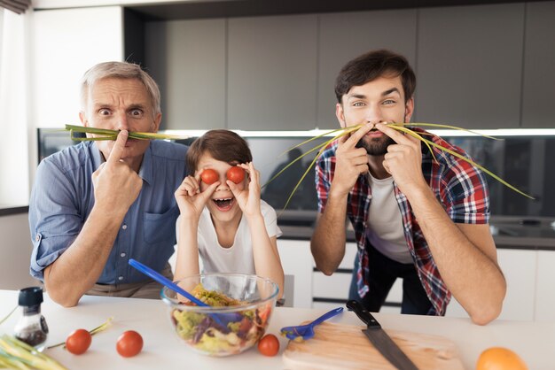 Un vieil homme, un homme et un garçon, font des grimaces.