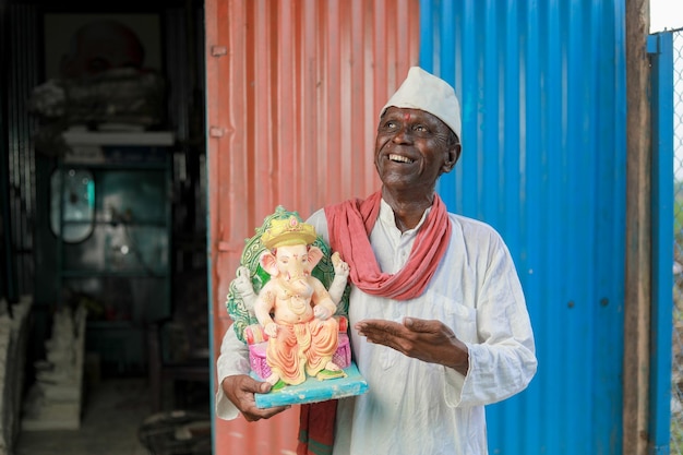 Un vieil homme indien tenant l'idole du Seigneur Ganesha dans ses mains un vieil homme pauvre heureux