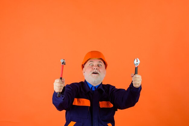 Vieil homme de l'industrie du bâtiment dans le constructeur de casque de construction avec des ingénieurs d'outils de réparation travaillant