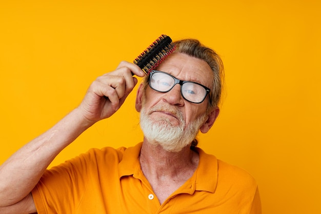 Un vieil homme à lunettes peigne ses longs cheveux gris