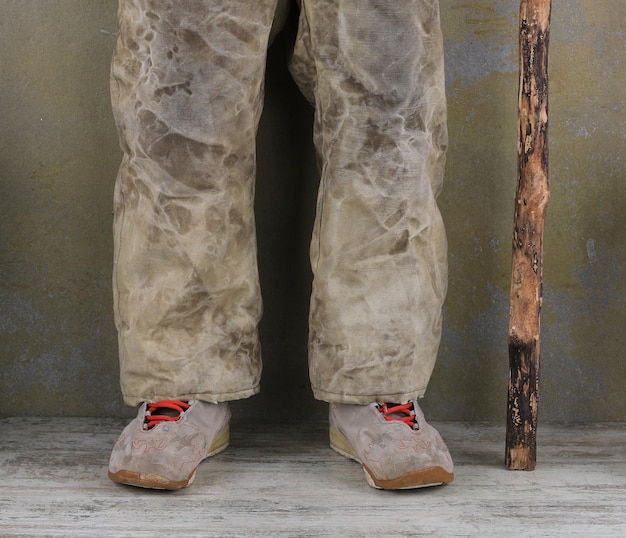 Photo un vieil homme en pantalon avec une béquille.