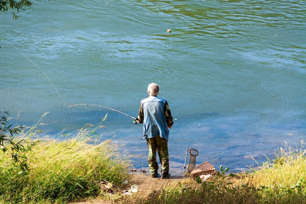 Un vieil homme pêche, un pêcheur, passe du temps dans la nature.