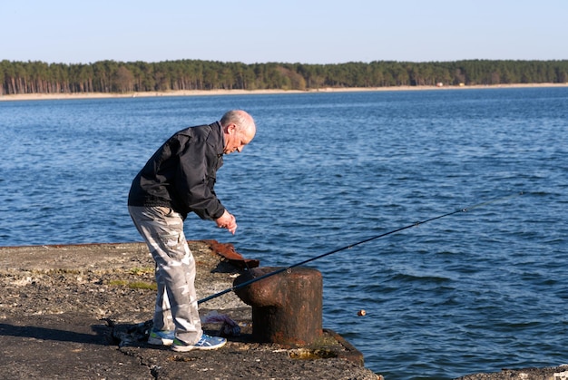 Un vieil homme pêche sur les rives de la mer Baltique à Tallinn