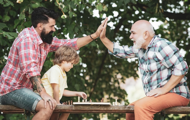 Vieil homme avec petit garçon jouant aux échecs mignon petit garçon jouant aux échecs avec les parents grand-père et gros