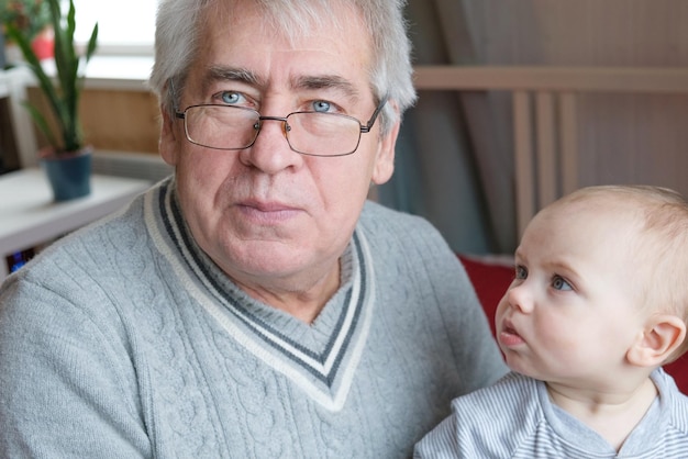 Un vieil homme et une petite fille heureux un vieil homme tient un petit enfant dans ses mains un petit-fils et un grand-père