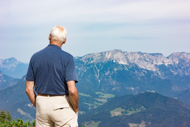 Un vieil homme regarde les montagnes alpines