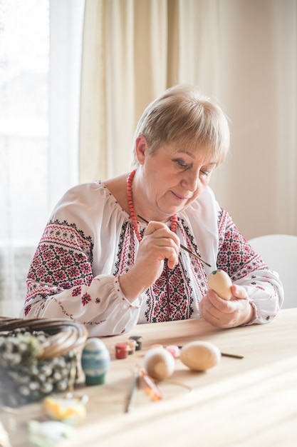 Un vieil homme à la retraite excité peint un œuf de Pâques Oeufs de Pâques bricolage