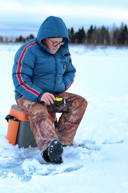 Vieil homme de saison d'hiver pêchant sur un lac