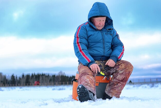 Vieil homme de saison d'hiver pêchant sur un lac