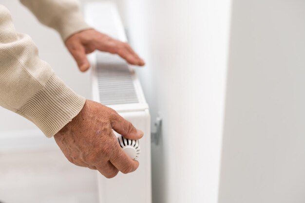 Un vieil homme se réchauffe les mains sur un radiateur électrique. En basse saison, le chauffage central est retardé, les gens doivent donc acheter des radiateurs supplémentaires pour garder les maisons au chaud malgré l'augmentation des factures d'électricité