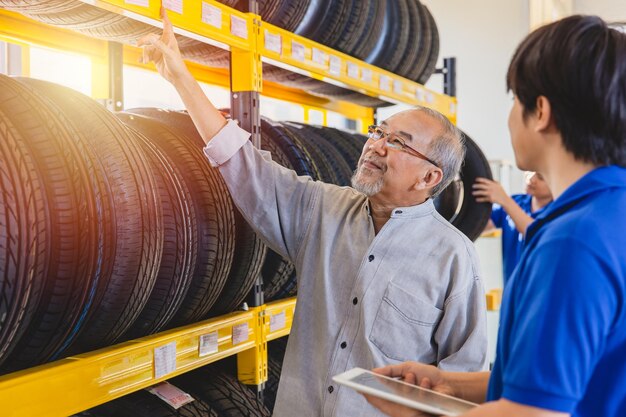 Vieil homme sélection client pneu de voiture dans le magasin de garage de pneus shopping heureux