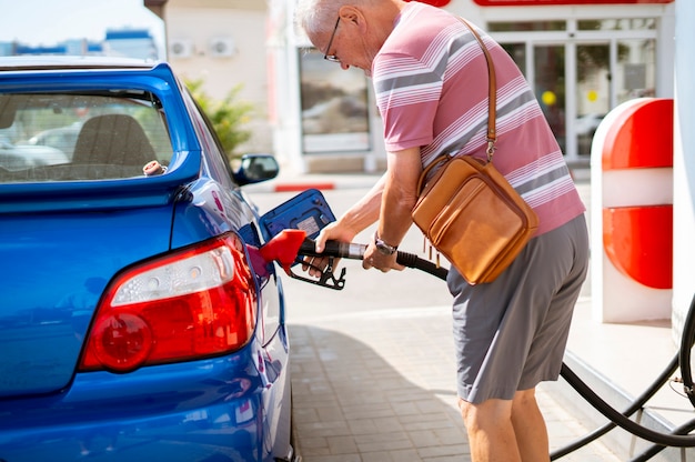 Le vieil homme senior remplir sa voiture avec de l'essence sur la station-service, les voyages touristiques