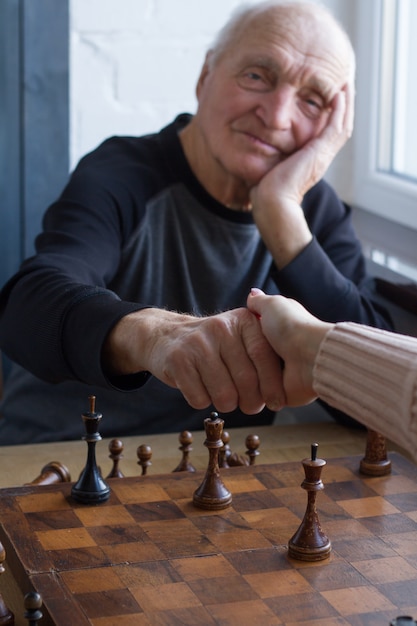 Photo un vieil homme serre la main avec un adversaire lors d'une partie d'échecs