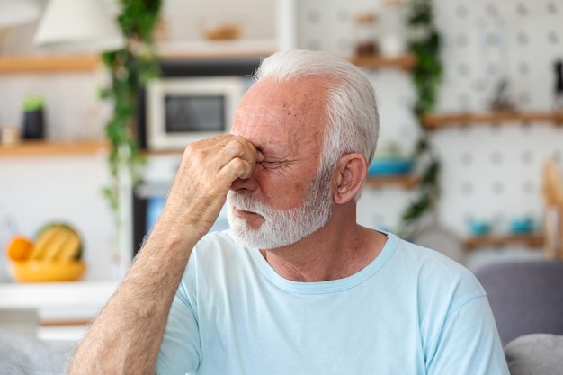 Un vieil homme souffre d'un mal de tête à la maison un vieil homme inquiet assis seul dans sa maison ce mal de tête me fait vraiment mal ma tête me tue