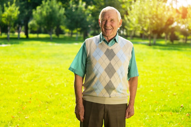 Vieil homme souriant en plein air.