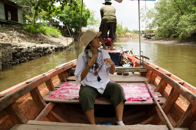 Un vieil homme thaïlandais chevauchant un bateau à longue queue amène les gens à visiter et à regarder la berge et la forêt de mangroves de la ville de Pak Nam Prasae le 10 août 2016 à Rayong en Thaïlande