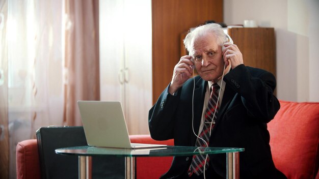 Un vieil homme tient des écouteurs avec ses mains et écoute la musique