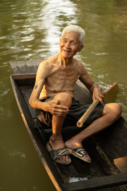 Vieil homme utilisant un bateau dans une ferme de noix de coco