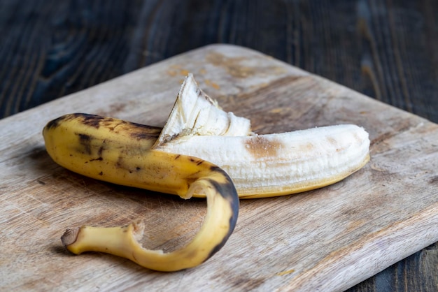 Vieille banane noircissante sur une planche à découper des aliments périssables aux fruits de la banane