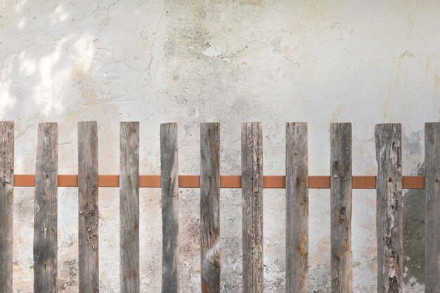 Vieille barrière en bois sur un fond de mur en pierre blanche