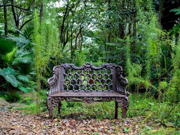 Vieille chaise de banquette en fer vintage solitaire vide dans la cour désolée sur le fond de la forêt verte