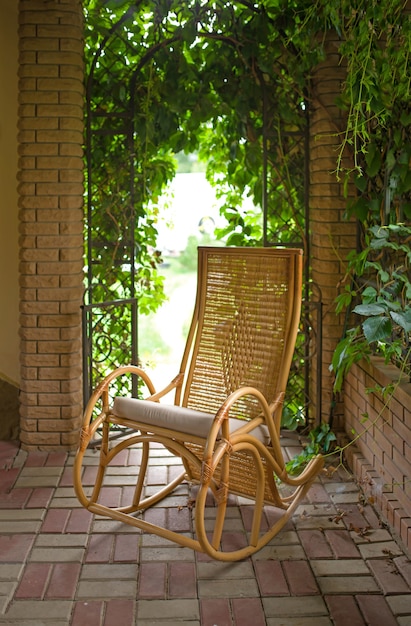 Vieille chaise berçante dans le belvédère Cheval rouge mangeant de l'herbe verte sur un champ près de maison et d'arbres à l'extérieur dans la campagne d'été