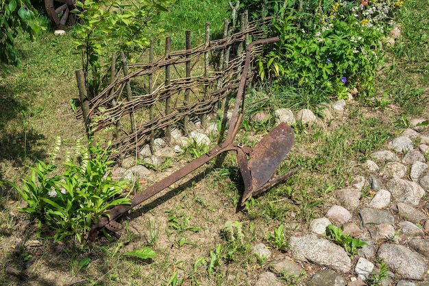 Vieille charrue rouillée pour labourer le sol allongé sur l'herbe