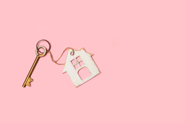Photo une vieille clé avec un porte-clés en forme de maison sur fond rose avec espace de copie