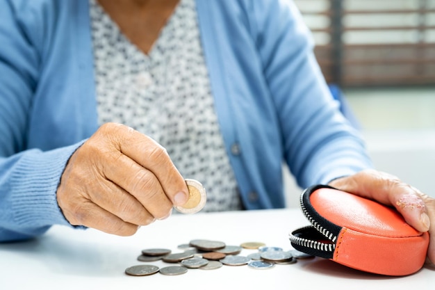 Une vieille dame âgée ou âgée asiatique tenant une pièce de monnaie dans un sac à main Problème d'épargne de la pauvreté à la retraite