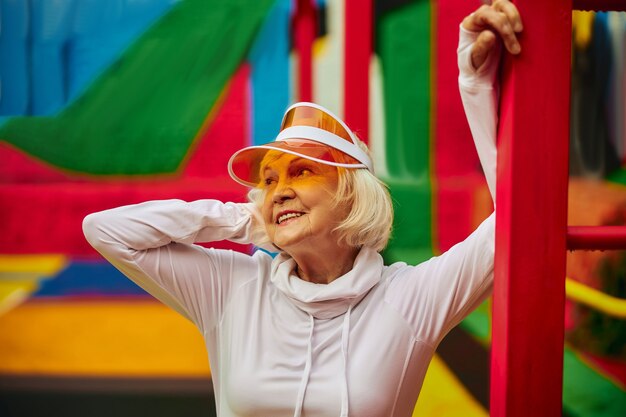 Vieille dame en bonne santé et joyeuse sur une place colorée à l'extérieur